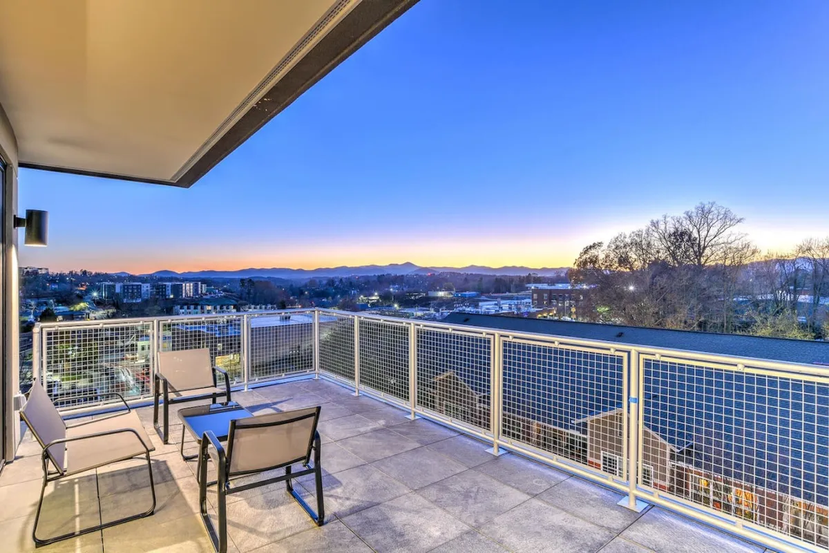 An inviting exterior shot of a balcony with chairs positioned towards a sweeping mountain view. The space is perfect for morning coffee or evening relaxation, framing the beautiful southern scenery.