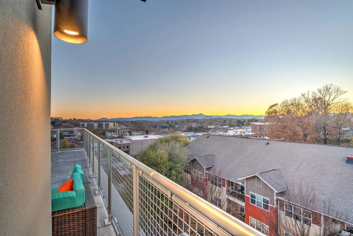 An exterior shot featuring a balcony with comfortable seating, overlooking a breathtaking mountain view and sunset-lit sky. The scene evokes serenity and offers an inviting space for relaxation or conversation, with nature as the backdrop.